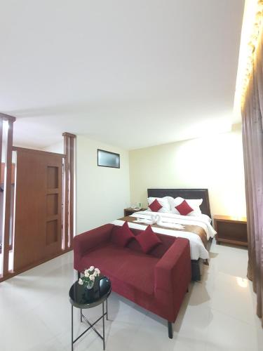 a bedroom with a bed and a red couch at Grand Mahoni Hotel in Banda Aceh