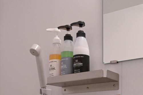 a shelf with four bottles of cleaning products at HOTEL R9 The Yard Sakaide in Sakaide