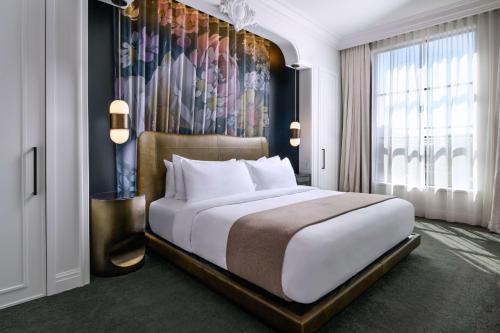 a bedroom with a large bed with a painting on the wall at Daxton Hotel Birmingham, Curio Collection by Hilton in Birmingham