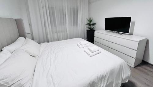a bedroom with a white bed and a tv at Nubia Modern Apartment in Craiova