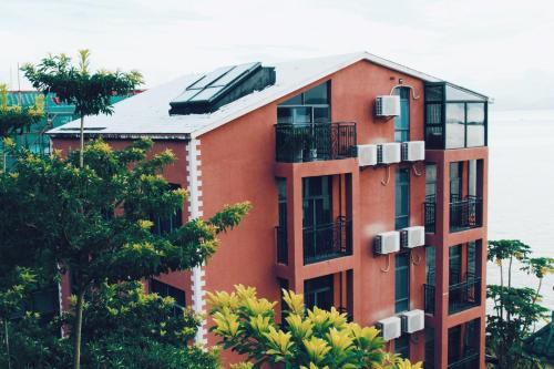 a red apartment building with trees in front of it at 深圳看见海海景精品民宿 in Shenzhen