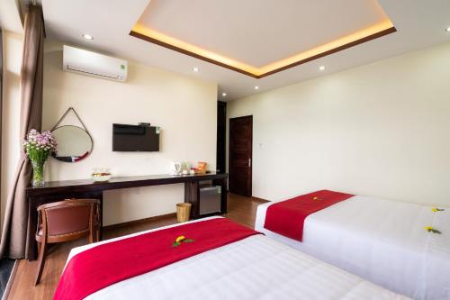 a bedroom with two beds and a desk with a mirror at Ancient River Villa in Hoi An