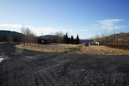 an empty road in a field with a house at Hlakot Cabin In Golden Circle in Mosfellsbær