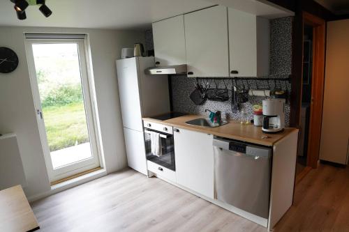 a kitchen with white cabinets and a sink and a window at Hlakot Cabin In Golden Circle in Mosfellsbær
