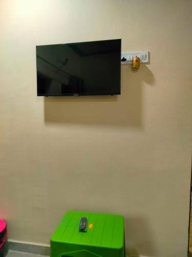 a flat screen tv hanging on a wall with a green stool at Shanti Paying Guest House in Mathura