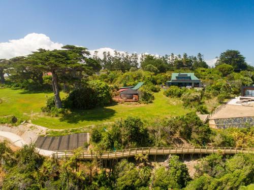 an aerial view of a house on a hill with a bridge at the hole in the rock yurt in Cape Foulwind