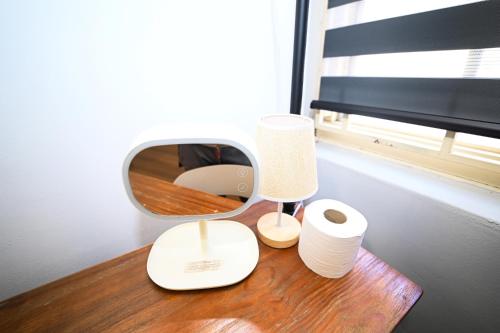 a table with a mirror and a lamp and toilet paper at Swing & Pillows @ Beach Street in George Town