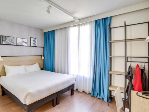 - une chambre avec un lit blanc et des rideaux bleus dans l'établissement ibis Levallois Perret, à Levallois-Perret
