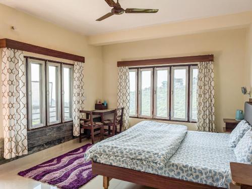 Un dormitorio con cama, escritorio y ventanas en Hobo Hostel, en Dharamshala