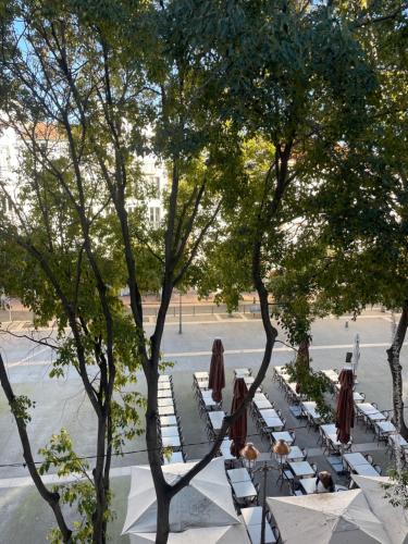 a group of tables with umbrellas and chairs under trees at Superbe appartement loft vieil Antibes in Antibes
