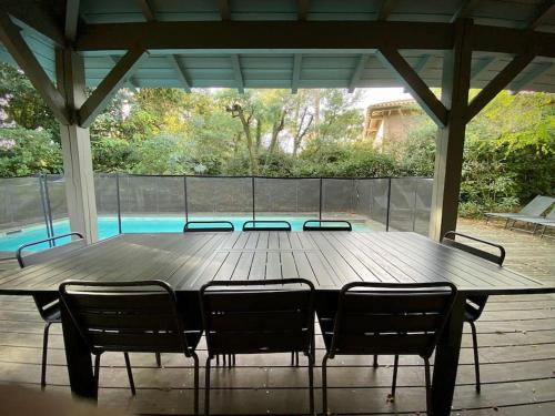 une table en bois avec quatre chaises assises autour de celle-ci dans l'établissement Villa Casa Manuela au Moulleau PYLA SUR MER, à Arcachon