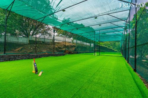 a batting cage with a green field of grass at EKOSTAY - Amanta Hills 7BHK in Karjat