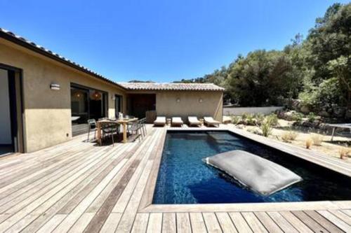 une piscine avec une terrasse en bois et une maison dans l'établissement Casa di Macchjerolu - 8 pers, à Sotta