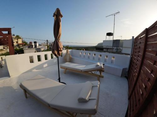 a patio with two chairs and an umbrella on a roof at Villa Benjamin in Milatos
