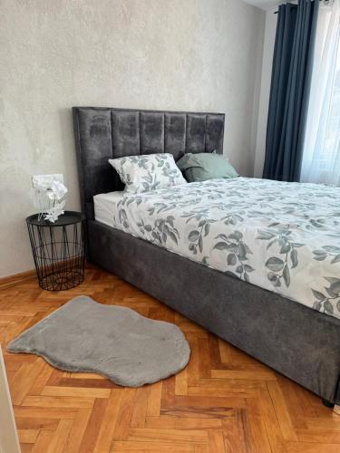 a bed in a bedroom with a rug on a wooden floor at Apartament ultracentral Tarnaveni in Tîrnăveni