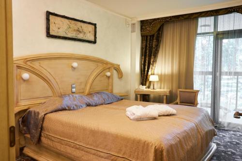 a bedroom with a bed with two towels on it at Grand SPA Lietuva Serviced Apartments Dzūkija in Druskininkai