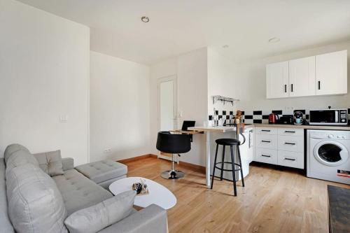 Il comprend un salon blanc avec un canapé et une cuisine. dans l'établissement Magnifique studio neuf aux portes de Paris, à Charenton-le-Pont