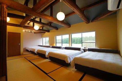a row of beds in a room with windows at Sauna Private Villa AO in Takashima