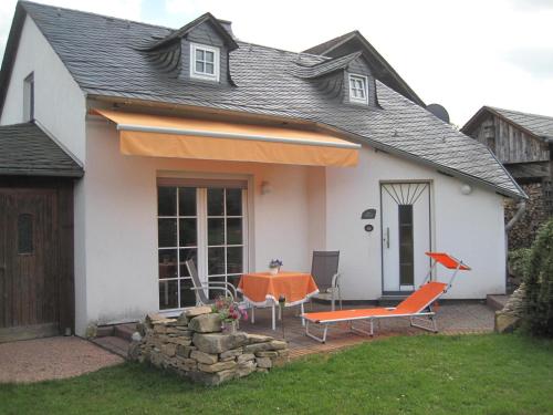 a house with a table and chairs in front of it at Landhaus Müller am Nationalpark Hunsrück-Hochwald in Schwollen