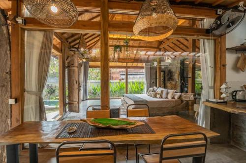 a dining room with a table and a couch at Villa Capung Padang Padang in Uluwatu