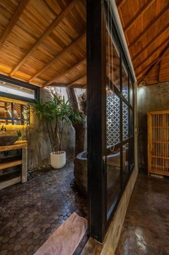 a room with a large glass door and a potted plant at Villa Capung Padang Padang in Uluwatu