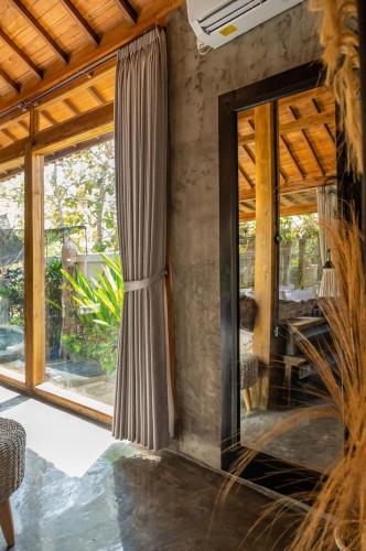 a room with a large glass window and a mirror at Villa Capung Padang Padang in Uluwatu
