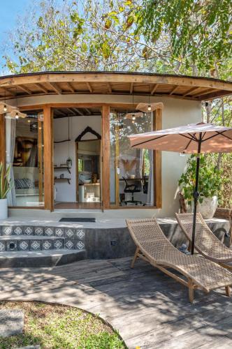 a patio with two chairs and an umbrella at Villa Capung Padang Padang in Uluwatu