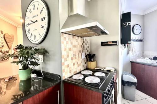 a kitchen with a clock on the wall and a stove at Afterglow Guesthouse in Reebok