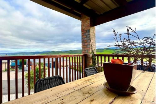 a wooden table with chairs on a balcony with a view at Afterglow Guesthouse in Reebok