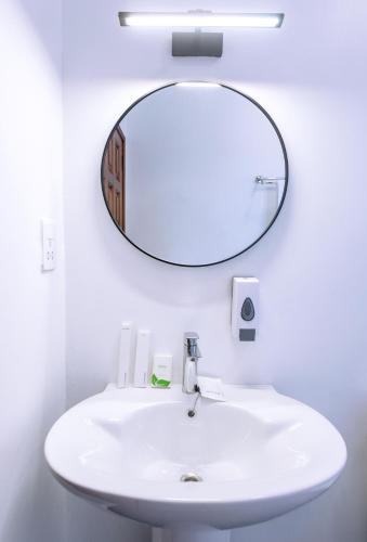 a bathroom with a white sink and a mirror at Tooro Green Courts in Namulanda