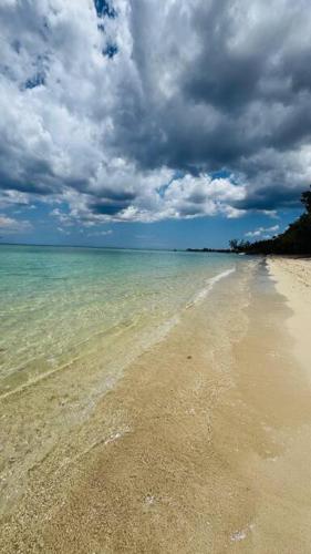 a beach with a cloudy sky and the ocean at La Passerelle des Empereurs in Albion