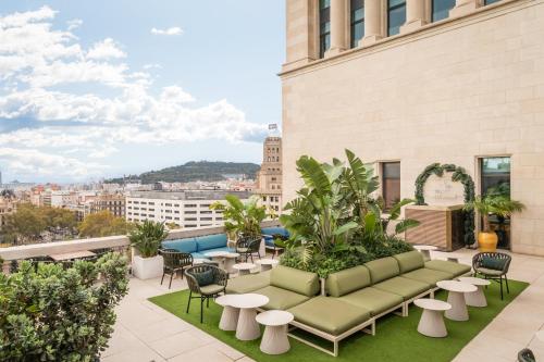 a rooftop patio with a couch and tables and chairs at 45 Times Barcelona Hotel in Barcelona