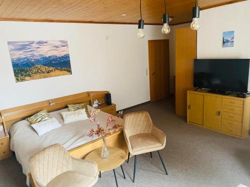 a bedroom with a bed with a television and chairs at Gasthof Frasswirt in Frass