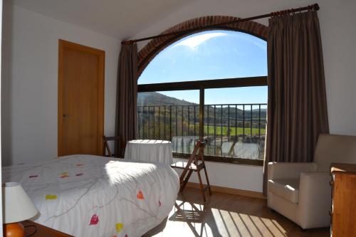 a bedroom with a bed and a large window at Masia Mol&iacute; de Tartareu in Tartareu