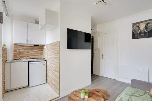 une cuisine avec des armoires blanches et une table dans une pièce dans l'établissement Appartement Suite 12 aux Portes de Paris, à Aubervilliers