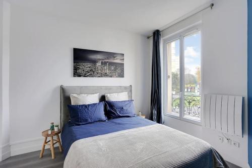 une chambre avec un lit avec des draps bleus et une fenêtre dans l'établissement Appartement Suite 12 aux Portes de Paris, à Aubervilliers