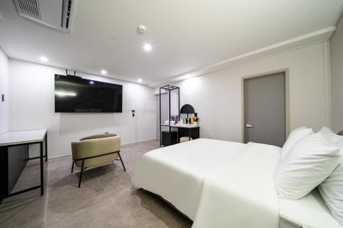 a bedroom with a white bed and a desk at Seosan Hotel Posto in Seosan