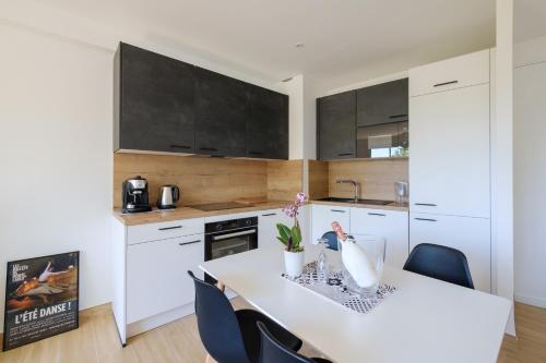 une cuisine avec des placards blancs et une table blanche avec des chaises dans l'établissement LA GRANDE BLEUE, Magnifique T2 climatisé, proche de la mer, à Menton