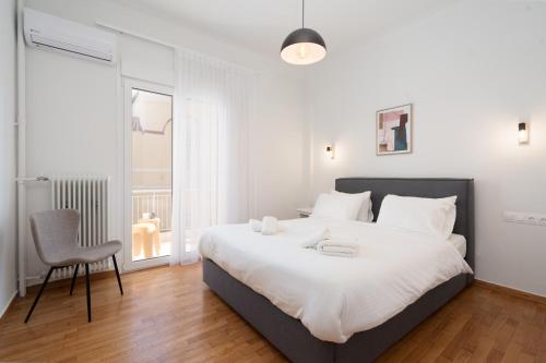 a bedroom with a large white bed and a chair at LIV - Elegant City Stay in Pagrati in Athens