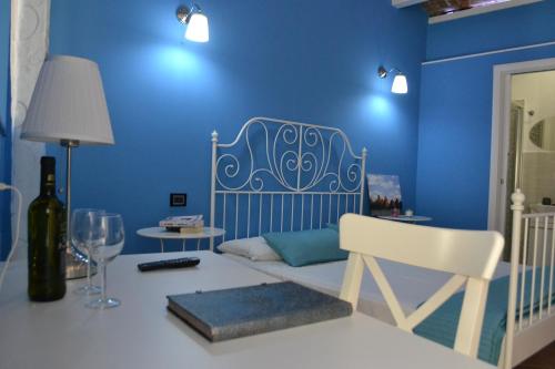 a blue room with a bed and a table with a wine glass at B&B O Casteddu in Monforte San Giorgio