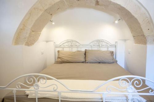 a bedroom with a white bed with an archway at Masseria Comara in Monopoli