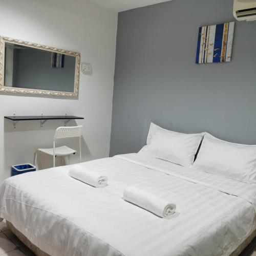 a white bed with two white pillows and a mirror at Hotel Seroja in Labuan