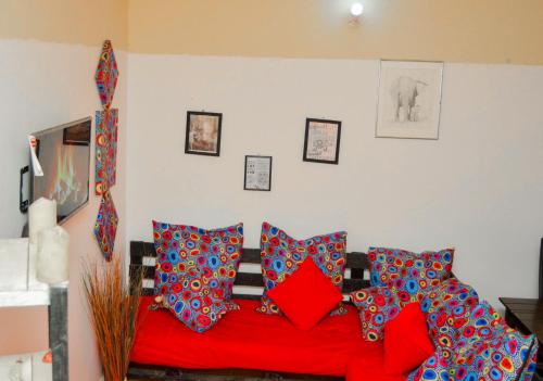 sala de estar con sofá rojo y almohadas en African themed one bedroom, en Diani Beach