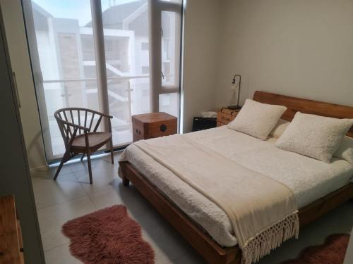 a bedroom with a bed and a chair and a window at Bellamare in Gqeberha