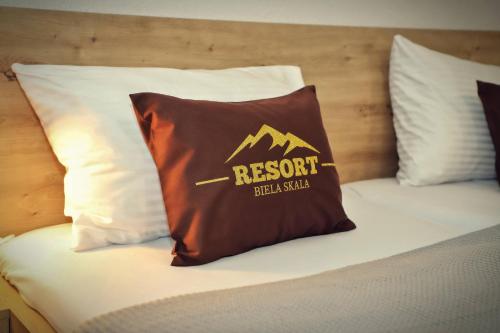 a pillow on a bed with a resort sign on it at Resort Biela Skala - CHATA Chopok Jasná Juh in Bystrá