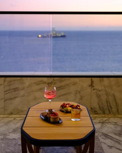 a table with a glass of wine and food on it at The Icon Limassol in Limassol