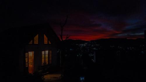 a house in the dark with a sunset in the background at The Mount Lodge in Nuwara Eliya