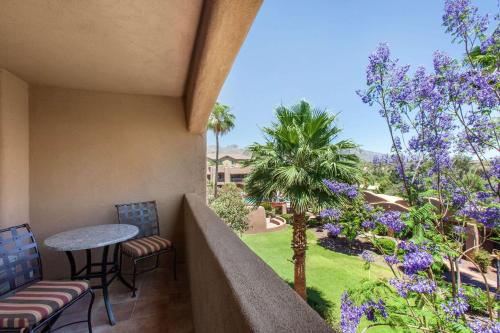 a balcony with a table and chairs and purple flowers at La Posada Lodge & Casitas, an Ascend Collection Hotel in Tucson