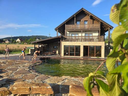 a group of people playing in a pool in front of a house at wellness Chata u Pinkasů in Písečná