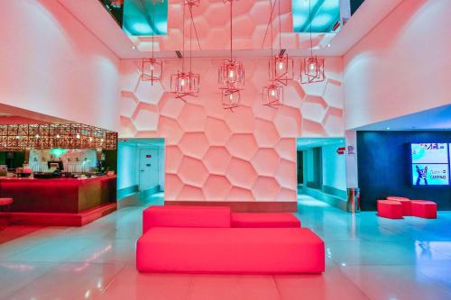 a living room with a red couch and a bar at Radisson RED Campinas in Campinas